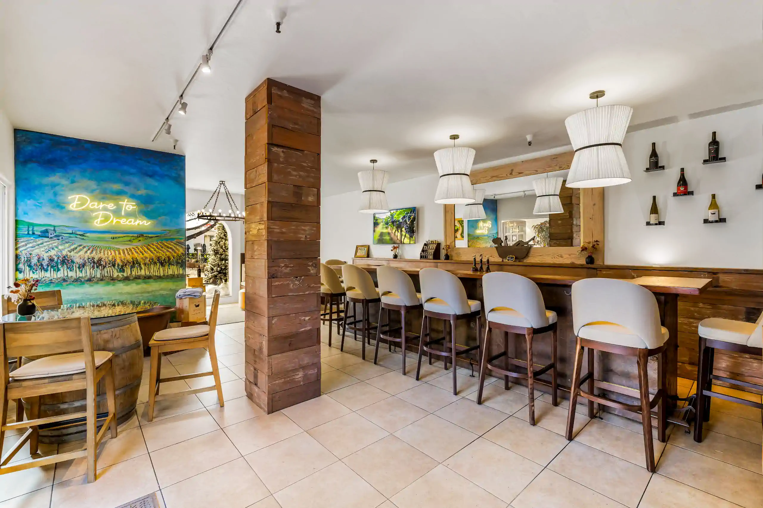 Cozy bar with wooden accents, high chairs, wall art, and a Dare to Dream mural in the background.